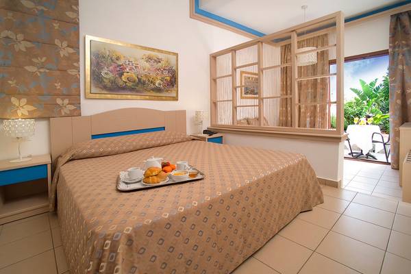 Ein Hotelzimmer mit einem Bett, auf dem eine Frühstücksplatte mit Tee, Croissants und Obst liegt.