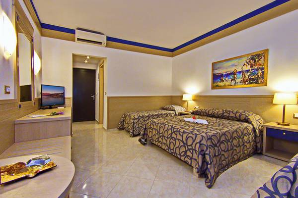 Ein Schlafzimmer im Nana Golden Beach Hotel mit zwei Doppelbetten, Nachttischen und einem Fernseher.