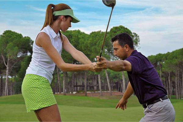 Golf Trainer und Kursteilnehmerin beim Training auf einem Golfplatz.