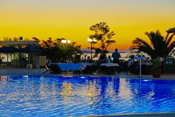 Sonnenuntergang am Nana Golden Beach Hotel mit Pool und Gästen an Tischen.