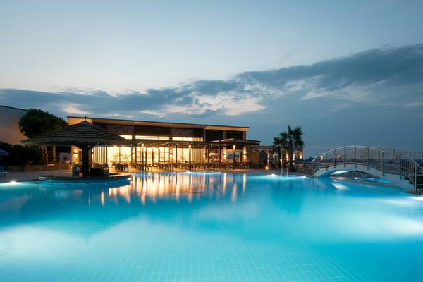 Der Außenpool des Nana Golden Beach Hotels am Abend mit beleuchtetem Gebäude und Brücke