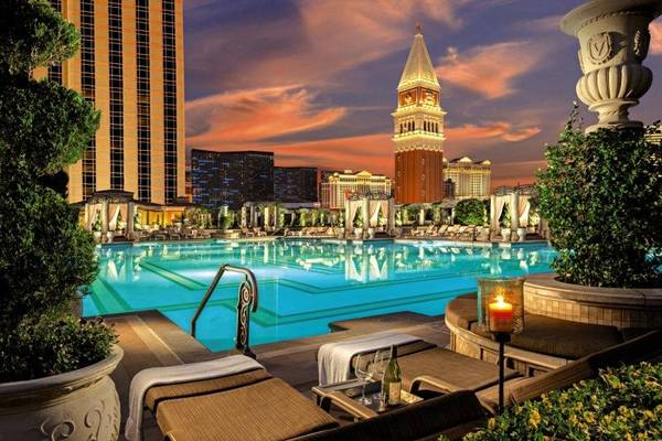 Außenpool des Venetian Resort Hotel & Casino bei Sonnenuntergang mit Lounge-Sesseln und Pflanzen