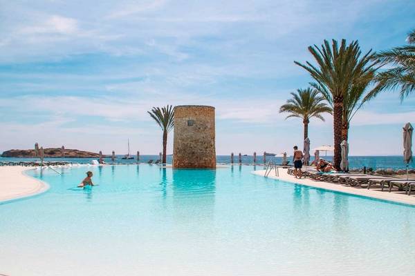 Außenpool des Torre del Mar Hotels mit Palmen, Liegestühlen und einem Turm