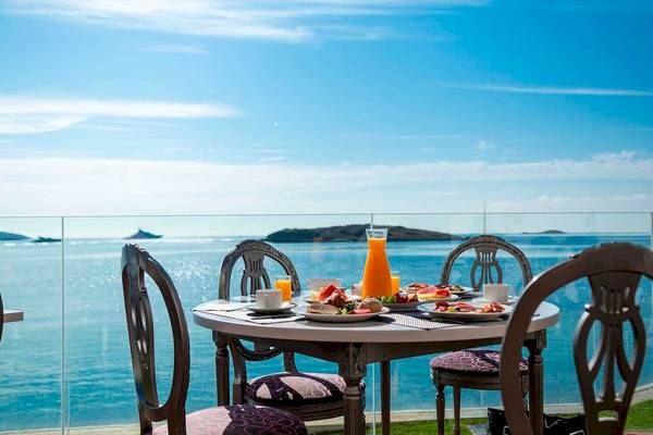 Frühstückstisch mit Meerblick im Torre del Mar Hotel mit einem Glas Orangensaft und Tellern mit Frühstücksgerichten.