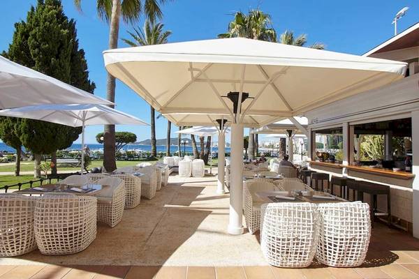 Außenterrasse des Torre del Mar Hotels mit weißen Möbeln und Sonnenschirmen.