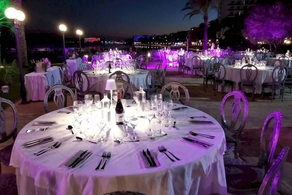 Abendessen im Freien bei Torre del Mar Hotel mit gedeckten Tischen und lila Beleuchtung.