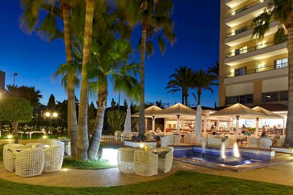 Außenbereich des Torre del Mar Hotels bei Nacht mit Beleuchtung und Gästen am Pool.