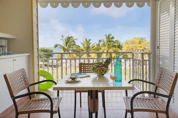 Terrasse der Apartments im Pierre & Vacances Village Club Sainte-Anne mit Blick auf das Meer und Palmen.