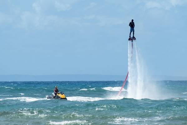 Zwei Personen genießen Wasserspaß im Ozean mit Jetskis und Fontänen.