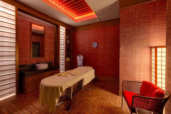 Massageraum im Susesi Luxury Resort mit rotem Dekor, Behandlungstisch und roten Stühlen.