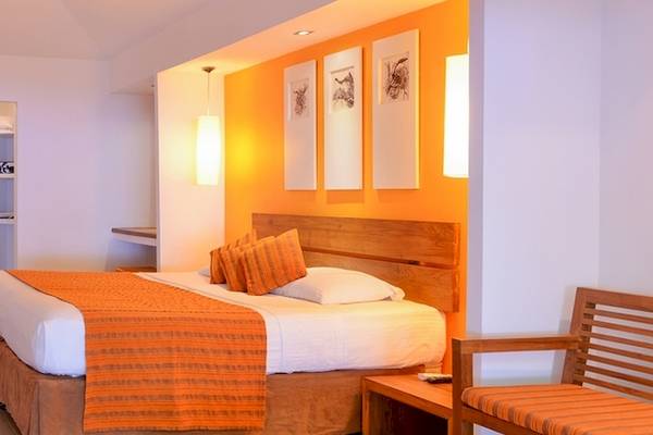 Innenansicht eines Hotelzimmers im Adaaran Select Hudhuran Fushi, mit Bett, Fernseher und Möbeln.