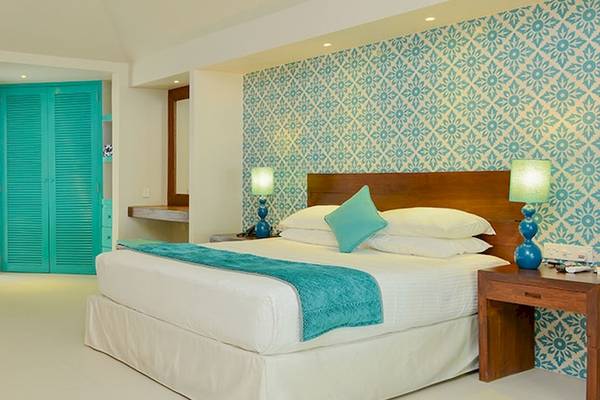 Hotelzimmer im Adaaran Select Hudhuran Fushi mit blauen Wänden, Bett, Chaiselongue und Schreibtisch.