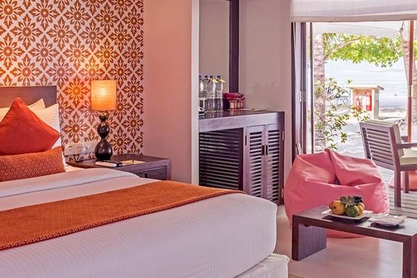 Hotelzimmer im Adaaran Select Hudhuran Fushi mit einem Bett, Kissen, Tisch, Lampe und einem Blick auf den Garten.