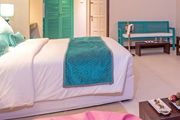 Hotelzimmer im Adaaran Select Hudhuran Fushi mit Bett, Früchteteller und Möbeln.