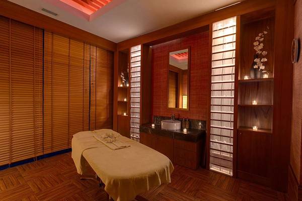 Massageraum im Susesi Luxury Resort mit einem Behandlungstisch, Waschbecken und dekorativen Elementen.
