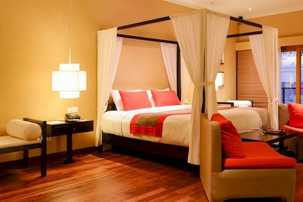 Hotelzimmer im Adaaran Select Hudhuran Fushi mit Himmelbett, Blick aufs Meer und modernem Interieur.
