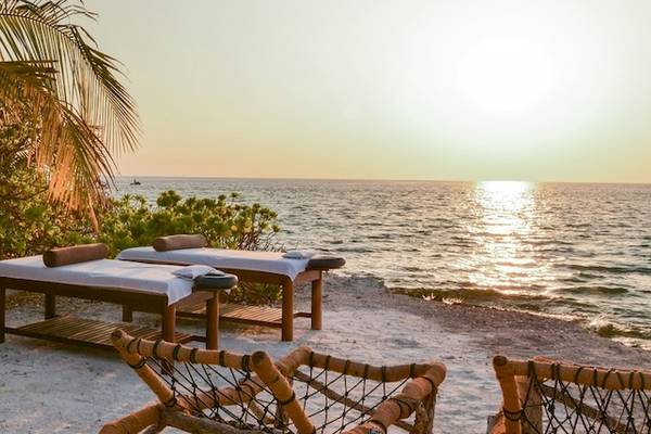 Außenbereich des Adaaran Select Hudhuran Fushi mit Massagebetten am Strand und Blick auf das Meer.