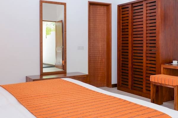 Hotelzimmer im Adaaran Select Hudhuran Fushi mit Bett, Spiegel, Fernseher und Schreibtisch.