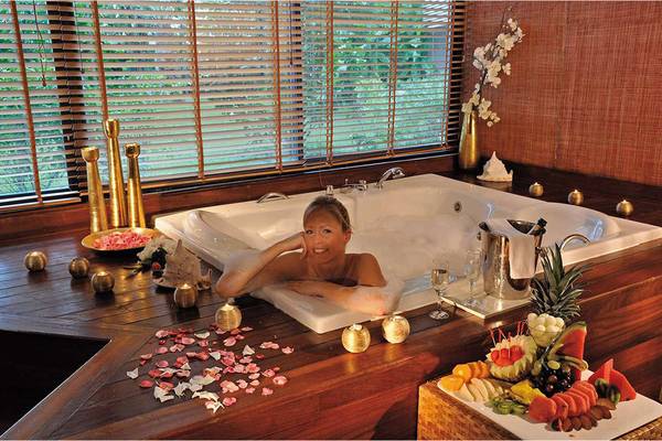 Frau in Luxus-Whirlpool im Susesi Luxury Resort mit Früchten und Kerzen