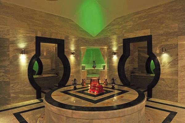 Innenansicht der Sauna im Susesi Luxury Resort mit grünem Licht und Marmorwänden.