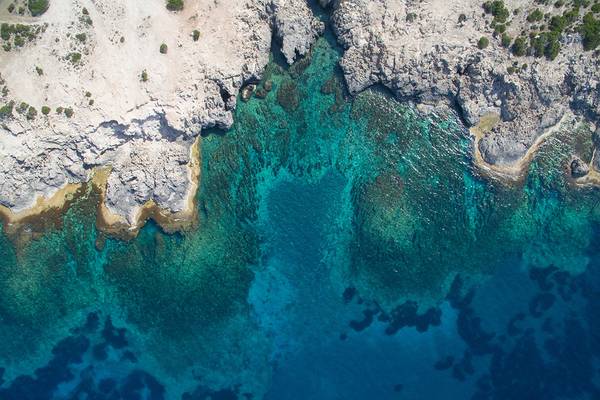 Luftaufnahme des blauen Wassers und felsigen Ufers bei Louis Paphos Breeze Hotel.