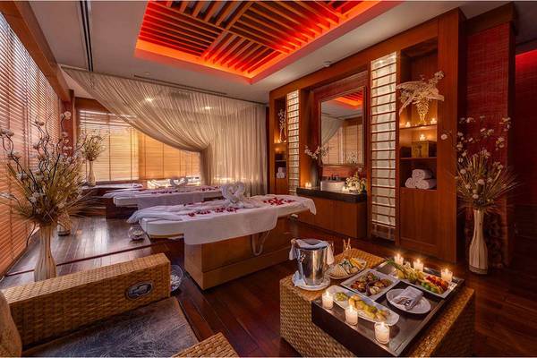 Massageraum im Susesi Luxury Resort mit zwei Massagetischen, Kerzen und Rosenblättern.
