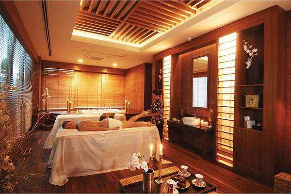 Spa-Behandlungsraum im Susesi Luxury Resort mit zwei Massagetischen, einer Person, die eine Massage erhält, und einer Mitarbeiterin.