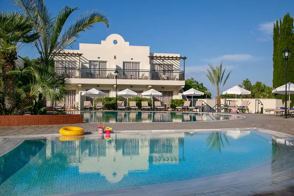 Außenansicht des Louis Paphos Breeze Hotels mit Swimmingpool, Sonnenliegen und Schirmen