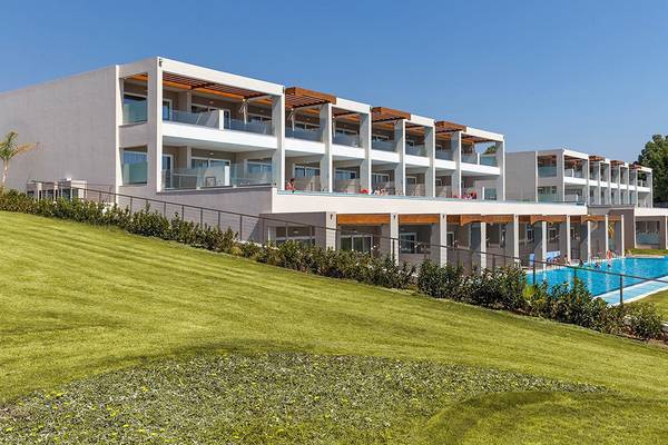 Außenansicht des Rodos Princess Beach Hotels mit mehreren Swimmingpools und Terrassen auf einem grün bewachsenen Hügel.