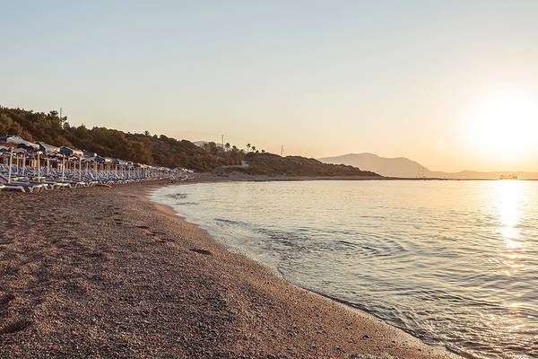 Sonnenuntergang am Strand des Rodos Princess Beach Hotels mit Sonnenschirmen und Liegestühlen.