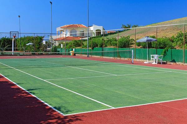 Tennisplatz vor dem Hotel Rodos Princess Beach mit einem Basketballkorb und einem Tisch mit Sonnenschirm.