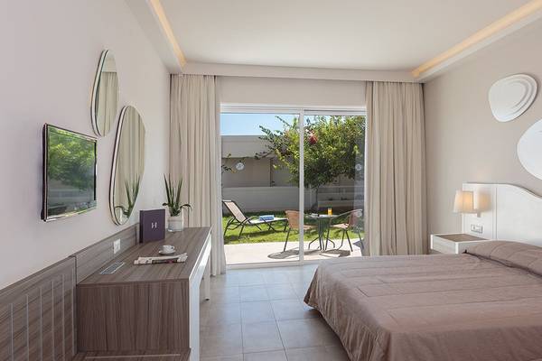 Innenansicht eines Hotelzimmers im Rodos Princess Beach Hotel mit Bett, Fernseher und Balkon.