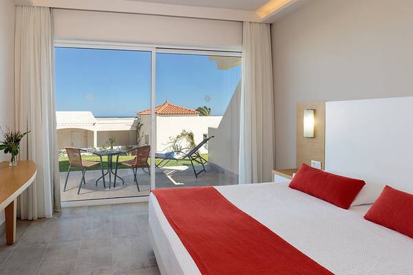 Hotelzimmer im Rodos Princess Beach mit Blick auf eine Terrasse und Gartenmöbel.