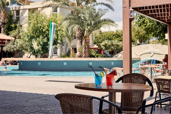 Blick auf die Poolbar des Esperides Beach Resorts mit Cocktails und Sonnenschirmen.