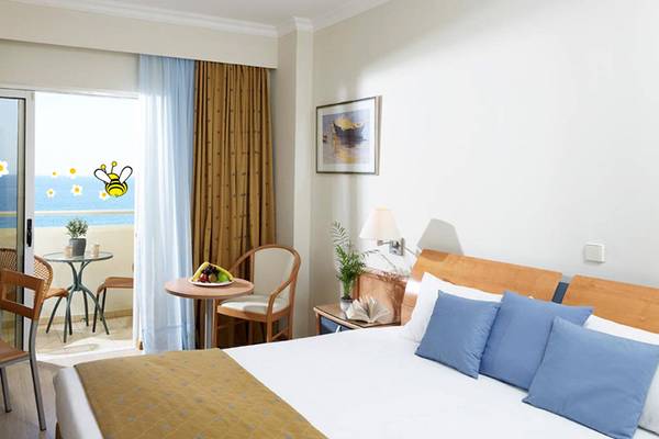 Doppelzimmer mit Meerblick im Esperides Beach Resort mit Balkon, Tisch, Stühlen und Bett.