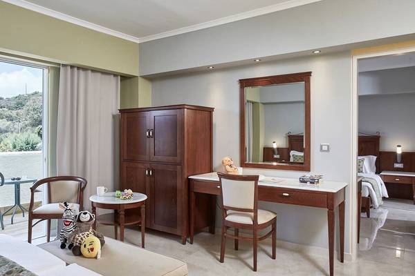 Innenansicht eines Zimmers im Esperides Beach Resort mit Schreibtisch, Stühlen, Kleiderschrank und Ausblick.