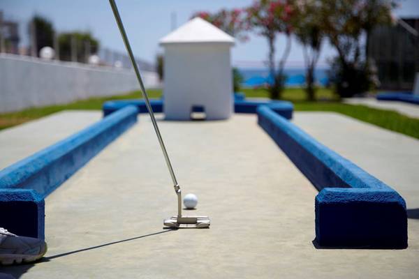 Miniatur-Golfplatz am Strand mit blauen Randsteinen und einem weißen Golfschläger.