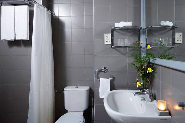Badezimmer im Esperides Beach Resort mit grauen Fliesen, einer Toilette, einem Waschbecken und Handtüchern