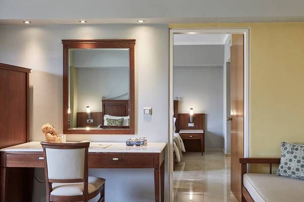 Inneneinrichtung eines Zimmers im Esperides Beach Resort mit Schreibtisch, Stuhl, Spiegel und Sofa.
