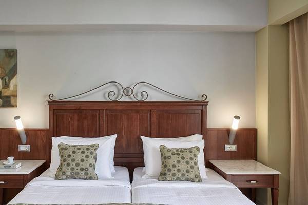 Doppelzimmer im Esperides Beach Resort mit zwei Betten, Nachttischen und Wandlampen.