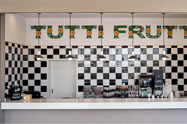 Bar im Hotel Esperides Beach Resort mit schwarz-weißem Schachbrettmuster und 'Tutti Frutti' Schriftzug.