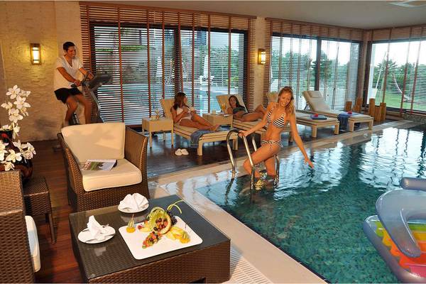 Poolbereich im Susesi Luxury Resort mit Liegestühlen, einem Mann auf einem Laufband und einer Frau, die in den Pool steigt.