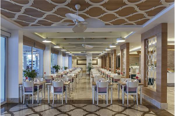 Restaurant im Privé Hotel Bodrum mit gedeckten Tischen, hängenden Deckenventilatoren und gemusterten Bodenfliesen.