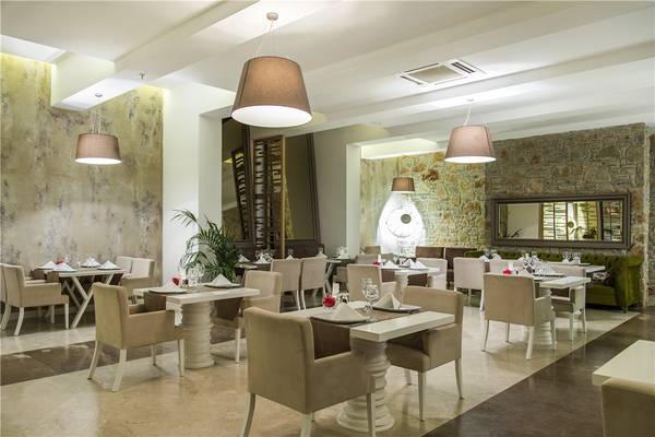 Das elegante Restaurant des Privé Hotel Bodrum mit weißen Tischen, Sesseln und Steinwänden.