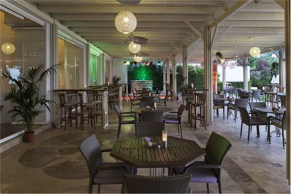 Außenbereich des Privé Hotel Bodrum mit Tischen und Stühlen unter einer Pergola.