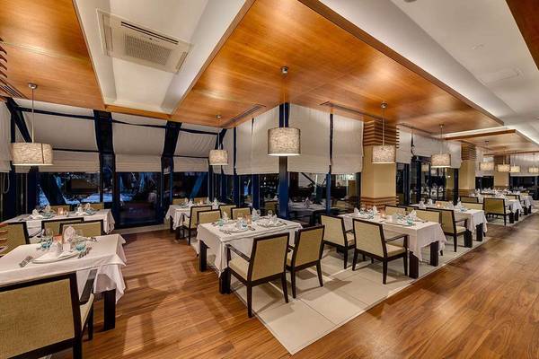 Innenansicht des Restaurants im Susesi Luxury Resort mit gedeckten Tischen und Holzböden.