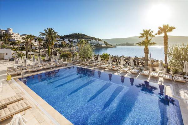 Prive Hotel Bodrum Außenpoolbereich mit Blick auf die Bucht und Palmen.