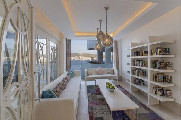 Wohnbereich des Prive Hotel Bodrum mit Sofa, Tisch und Bücherregal.