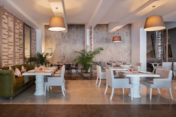 Innenbereich des Privé Hotel Bodrum Restaurant mit weißen Tischen, Sesseln, Pflanzen und Marmorboden.