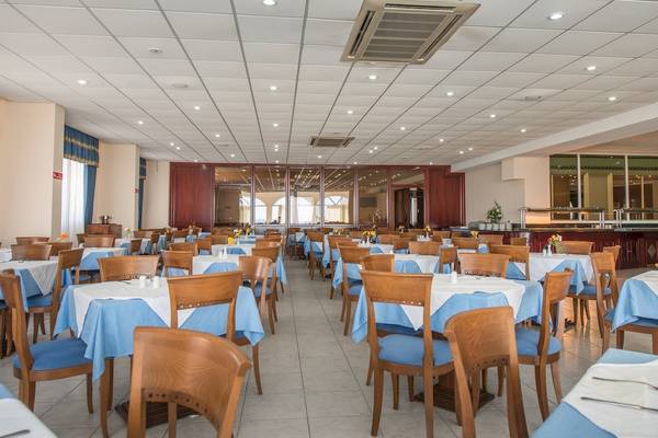 Innenansicht des Restaurants im Astir Palace Hotel mit blauen Tischdecken und Holzstühlen.